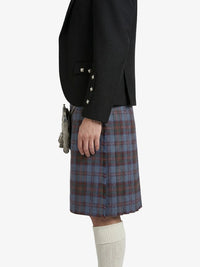Person wearing a black blazer and plaid kilt on a white background
