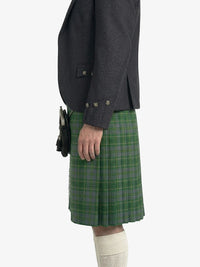 Person wearing a dark gray jacket and green plaid kilt on a white background