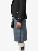 Person wearing a black jacket and blue plaid kilt on a white background