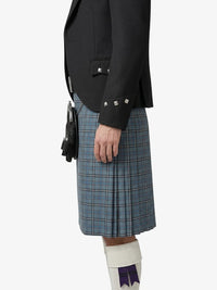 Person wearing a black jacket and blue plaid kilt on a white background