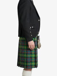 Person wearing a black jacket and green plaid kilt on a white background