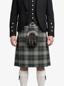 Person wearing a traditional Scottish kilt with a jacket and white socks on a white background