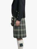 Person wearing a black jacket and plaid kilt on a white background